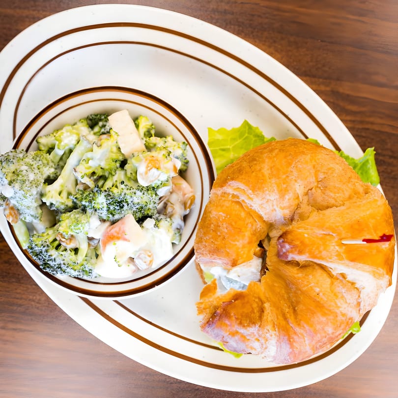 PerKup Cafe's croissant sandwich with lettuce and a side of creamy broccoli salad.
