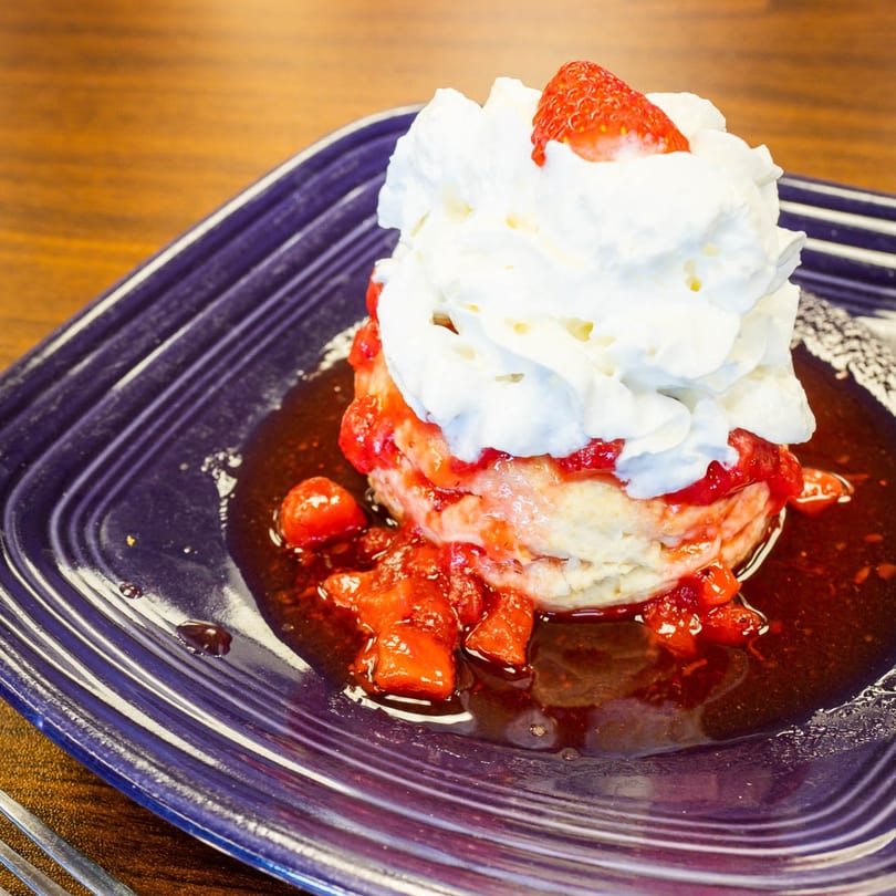 PerKup Cafe's strawberry shortcake with whipped cream and strawberry topping on a purple plate.